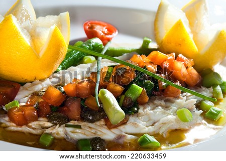 macro fish dish is exquisitely decorated on a white plate with lemon and vegetables