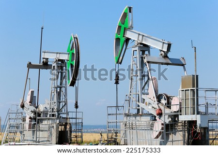 summer landscape oil pumps in the grain fields on the background of the blue sky on a sunny day