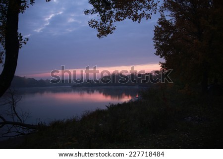 autumn landscape beautiful pink sunset on the river and trees, clouds reflected in water