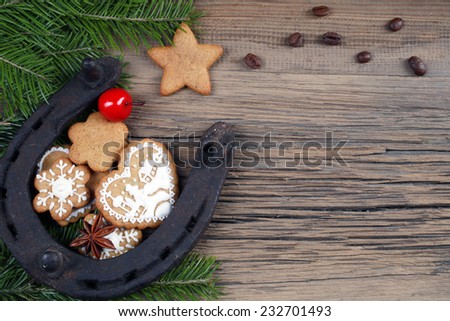 close-up still-life of fir branches, the horseshoes and gingerbread with pattern on magic Christmas holiday on background a wooden boards studio