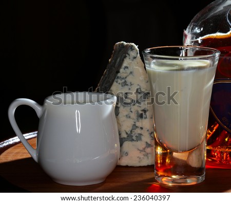 close-up of a still life with glass of warming drinks on the background bottles, jugs and a piece of cheese