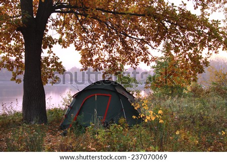 autumn landscape tourist tent under yellow oak near the river