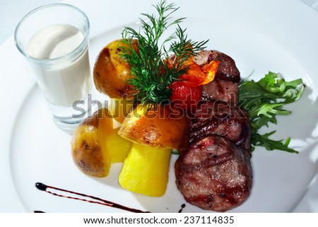 macro a second dish pork medallions garnished with potatoes cut in the shape of mushrooms and cream sauce on a white plate studio