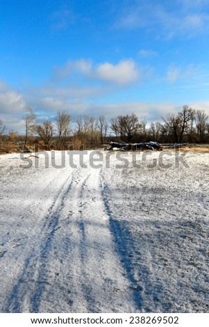 winter landscape snow-covered dirt road at the beginning of winter in a sunny day