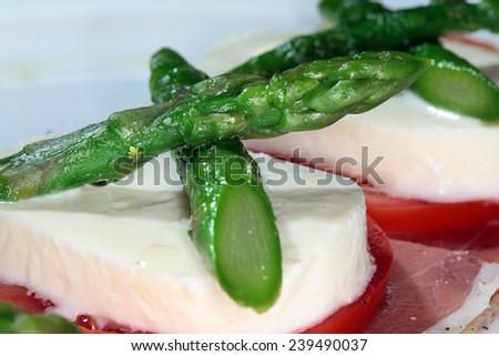 Close-up of bacon with cheese, tomato and asparagus on a white plate on a black background studio