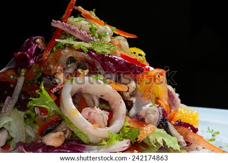 close-up of exquisite seafood salad with fresh herbs and vegetables on a white plate