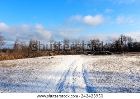 winter landscape snow-covered dirt road at the beginning of winter in a sunny day