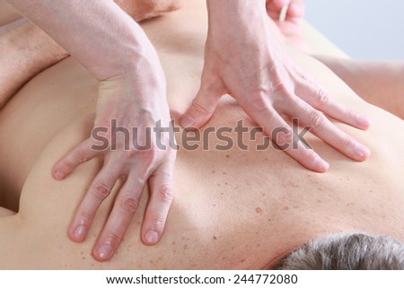Isolated close-up of the hands of the masseur - female on man's back during a session, studio