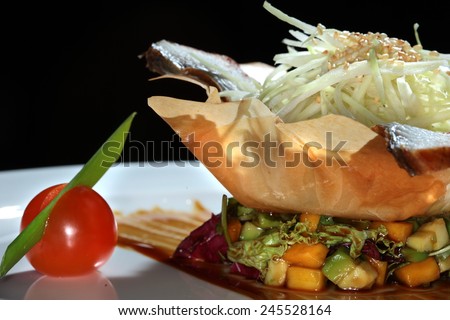 close-up gourmet salad with fish and vegetables in a basket made of dough on black background studio