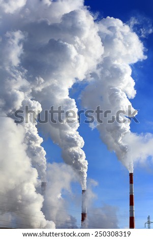 isolated close-up of white smoke from the chimney of the plant against the blue sky