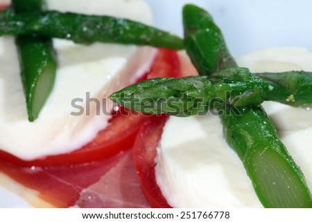 Close-up of bacon with cheese, tomato and asparagus on a white plate on a black background studio