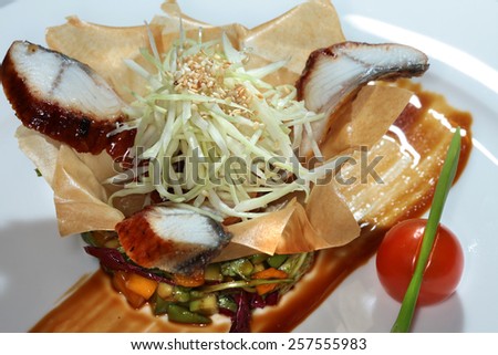 close-up gourmet salad with fish and vegetables in a basket made of dough on black background studio