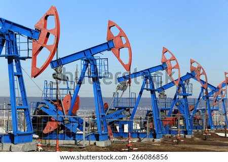 industrial landscape oil pumps in the early spring on a blue sky background