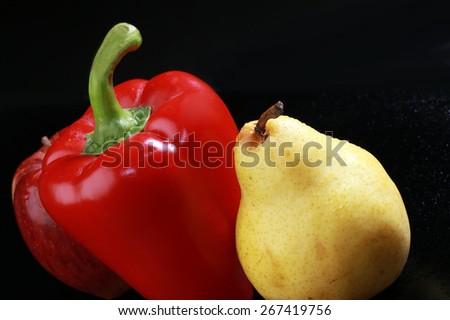 macro yellow pear, red apple and red bell peppers on black background studio
