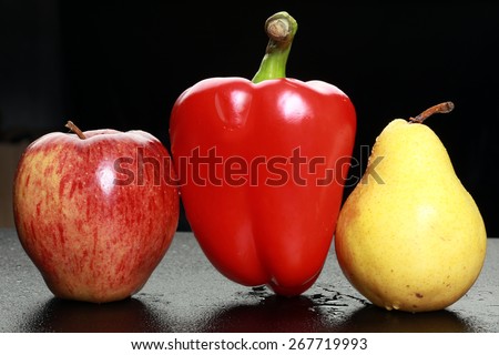 macro yellow pear, red apple and red bell peppers on black background studio