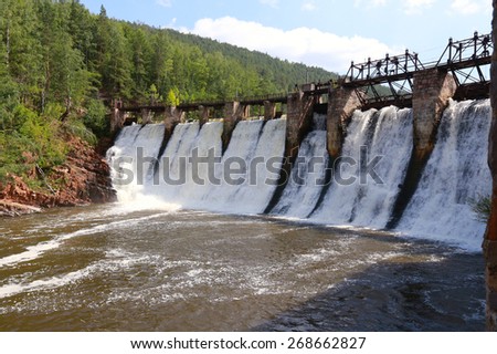 summer landscape of the old dam on the river on a background of mountains and woods on a sunny day