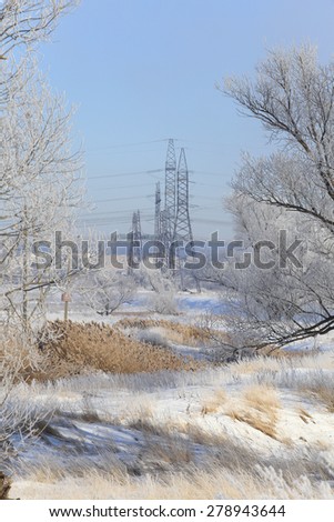 winter landscape dense fog over fields and high-voltage power line on the horizon at sunrise