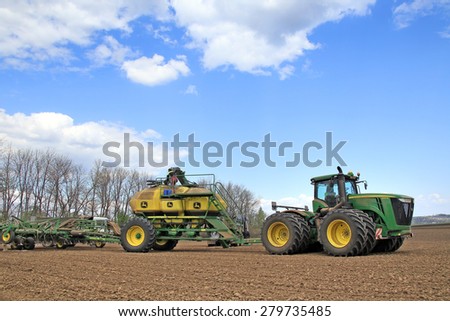 Naberezhnye Chelny, Russia - May 12, 2015: Planting in the field with the help of modern John Deere tractor on a sunny spring day