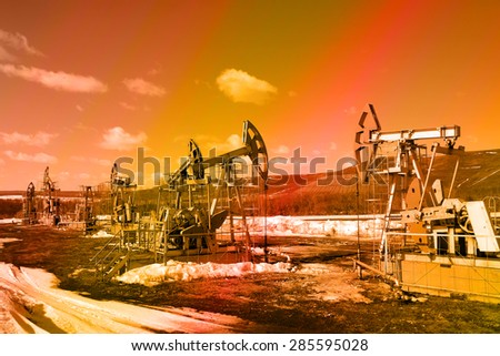 industrial landscape Oil pumps in the field on a background of sky on a sunny day in early spring instagram filter