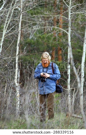 portrait photographer with a red beard and a mustache in a meadow in early spring