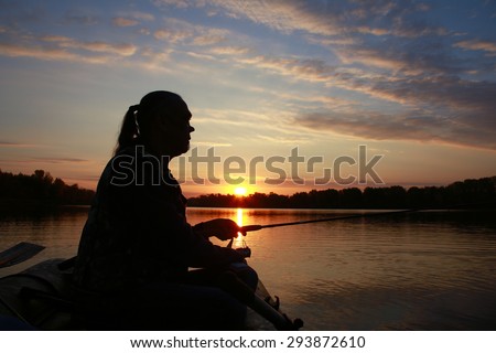 Portrait of a man in profile in a boat on a river with a fishing pole in his hands at sunset in autumn