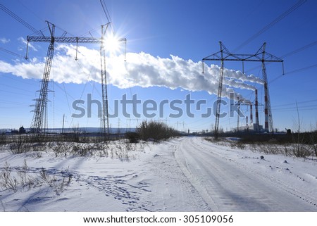 power lines along the snow-covered winter road on a sunny day on blue sky background