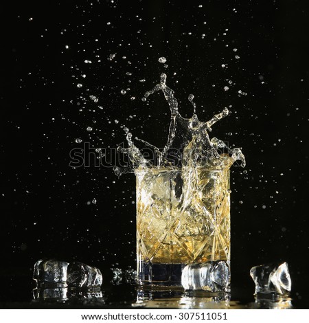 An isolated shot of whiskey with a splash on a black background