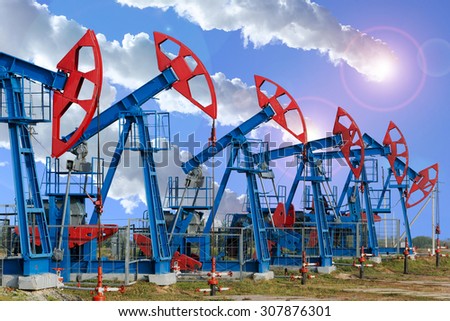 close-up of oil pumps on background of dramatic clouds at sunset