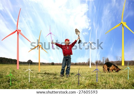 Smiling happy little boy with small windmill and spade. He is planting small windmills on green meadow by spring with his dog.