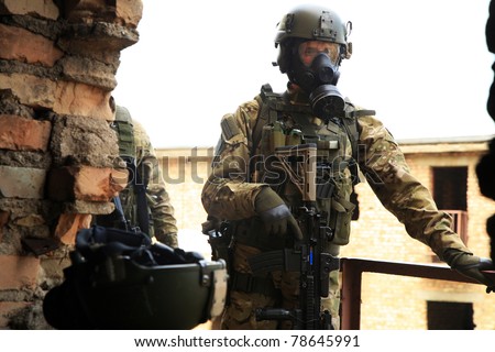 Special forces soldier during a black tactical exercises. Army Soldier  in full tactical gear with weapons  and gas mask. Real situation.