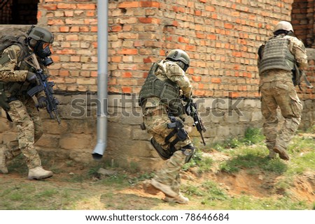 Special forces soldier during a black tactical exercises. Army Soldier  in full tactical gear with weapons  and gas mask. Real situation, action.