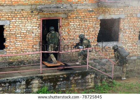 Special forces soldier during a black tactical exercises. Army Soldier  in full tactical gear with weapons  and gas mask. Intrusion inside the building after the detonation of an explosive.