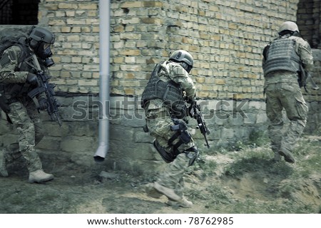 Special forces soldier during a black tactical exercises. Army Soldier  in full tactical gear with weapons  and gas mask. Real situation, action.