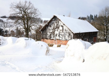 Barn and bale of straw in snow. Winter scenery on the farm.