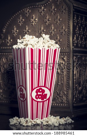 Close crop of a popcorn container filled with popcorn with a vintage national cash register in the background