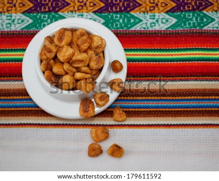 Small bowl of toasted salted corn seeds on peruvian tablecloth