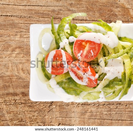 Overview of cucumber and tomato salad on old wooden table
