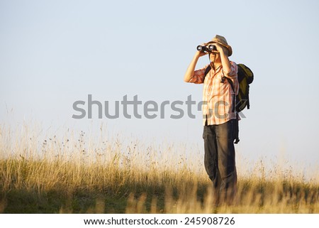Hiker standing in field with binoculars