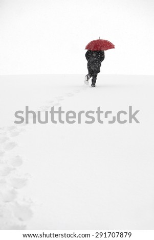 Man walking in winter snow storm in the snow next to the forest