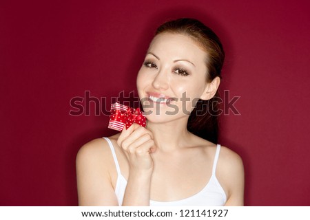 Attractive Female smiling biting lower lip with a small gift