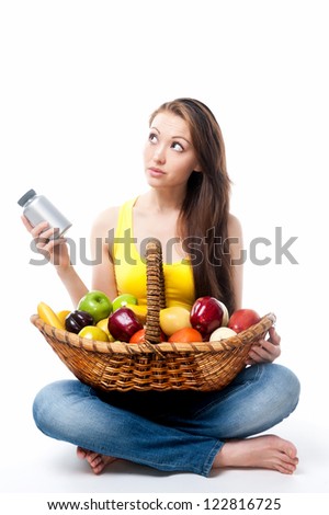 Attractive Mixed Asian female thinking with fruit basket and supplement bottle