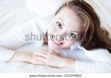Attractive Asian Mixed Woman smiling in bed looking ahead