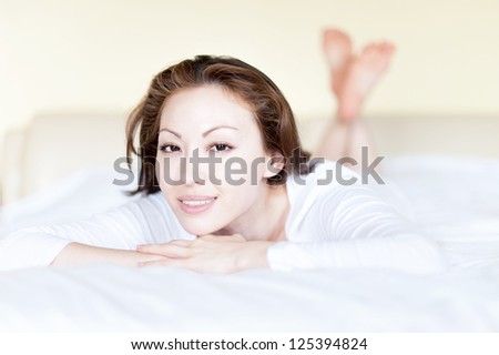 Attractive Asian Mixed Woman in Bed Smiling with crossed legs