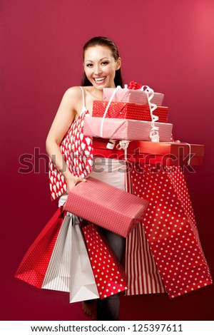 Attractive Asian Mixed Woman smiling cheekily with gifts and shopping bags
