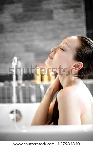 Attractive Mixed Asian Female enjoying bath with eyes closed