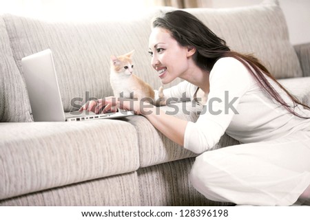 Attractive mixed asian woman with kitten using the laptop