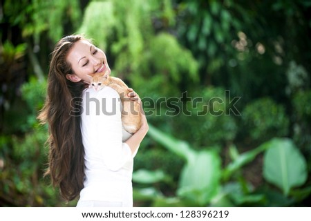 Attractive mixed asian woman holding kitten to chest