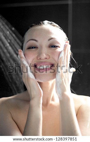 Attractive mixed asian woman washing face in shower with soap