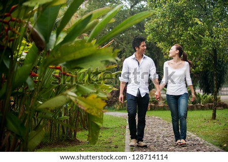Attractive Asian Couple walking hand in hand in park