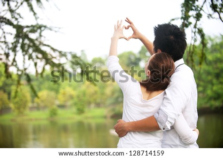 Attractive Asian Couple Making A Love Symbol With Hands